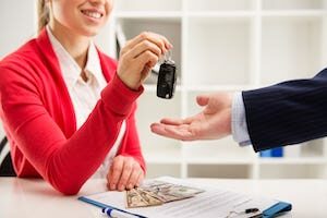 Sales manager women handing over the keys to an auto customer after receiving a successful payment